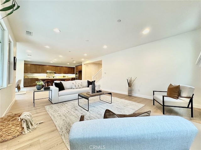 living room featuring visible vents, baseboards, stairs, light wood-type flooring, and recessed lighting