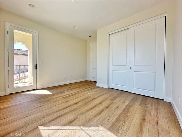 unfurnished bedroom featuring a closet, baseboards, and light wood-style floors