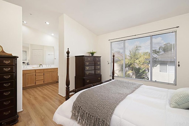 bedroom featuring ensuite bathroom, a sink, recessed lighting, light wood finished floors, and vaulted ceiling