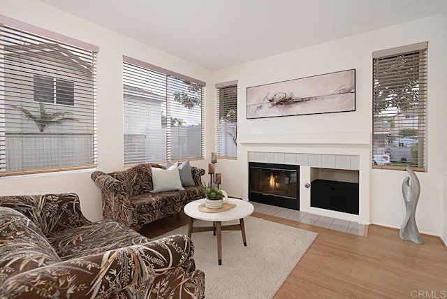 living room with a tile fireplace, baseboards, and wood finished floors