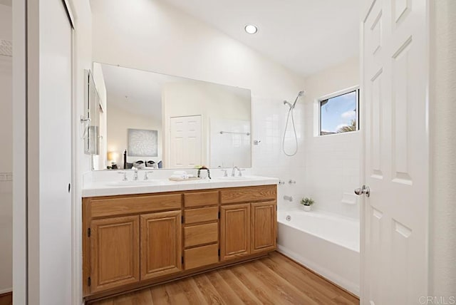 full bathroom featuring ensuite bathroom, a sink, wood finished floors, double vanity, and bathing tub / shower combination