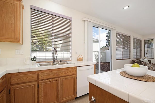 kitchen with tile counters, a sink, recessed lighting, and white dishwasher