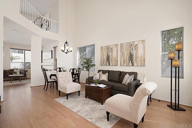 living room with a high ceiling, a notable chandelier, and light wood finished floors