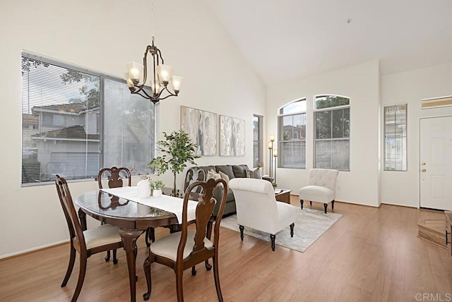 dining area featuring a notable chandelier, high vaulted ceiling, and wood finished floors