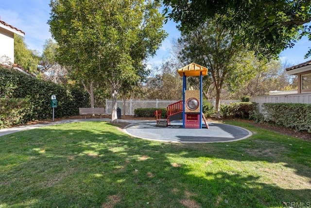 communal playground featuring a lawn and fence