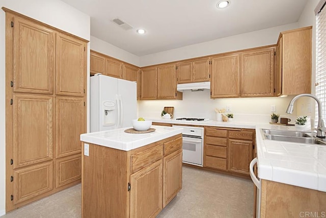 kitchen with white appliances, tile countertops, visible vents, a sink, and under cabinet range hood