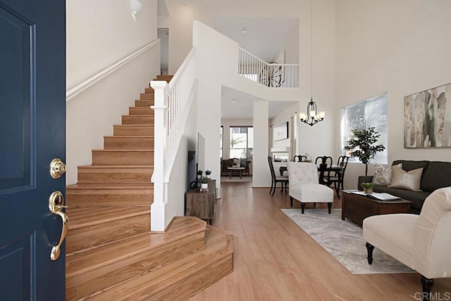 entrance foyer with stairway, a high ceiling, an inviting chandelier, and wood finished floors