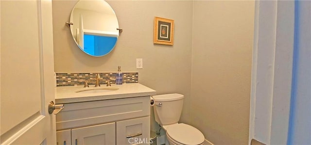 bathroom with decorative backsplash, toilet, and vanity