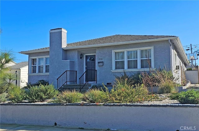 bungalow-style home with a chimney and stucco siding