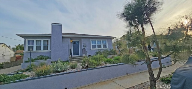 view of front facade featuring a chimney and stucco siding