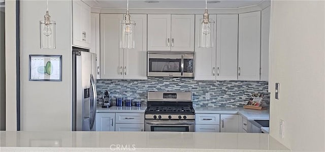 kitchen with pendant lighting, white cabinetry, appliances with stainless steel finishes, light countertops, and decorative backsplash