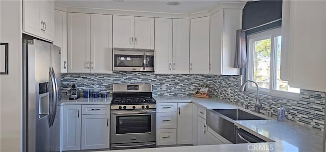 kitchen featuring decorative backsplash, white cabinets, appliances with stainless steel finishes, and a sink