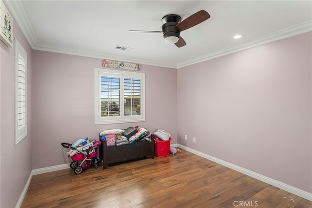 rec room with hardwood / wood-style floors, visible vents, baseboards, ceiling fan, and crown molding