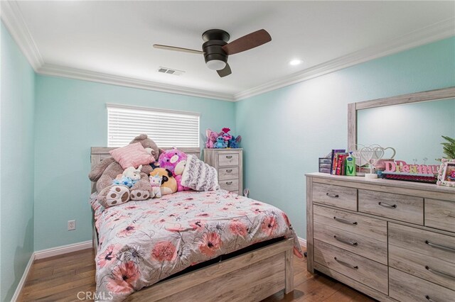 bedroom with visible vents, crown molding, baseboards, a ceiling fan, and wood-type flooring