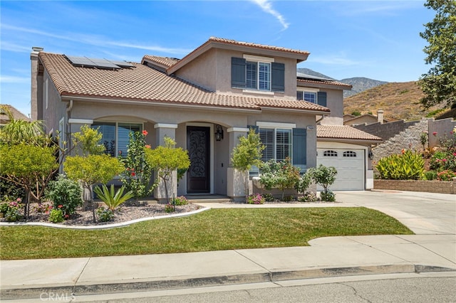 mediterranean / spanish house with stucco siding, driveway, a tile roof, and a front lawn