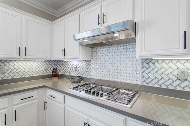 kitchen with ornamental molding, under cabinet range hood, backsplash, stainless steel gas stovetop, and white cabinets