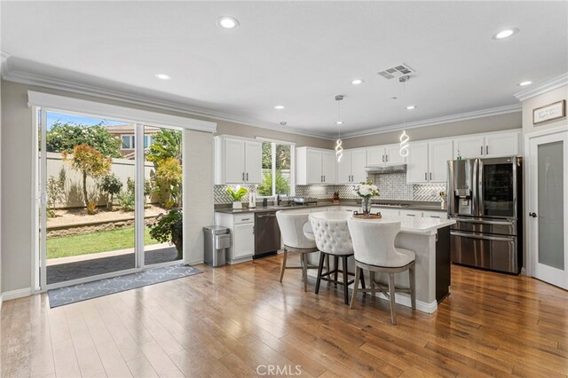 kitchen featuring visible vents, stainless steel appliances, dark wood-type flooring, a kitchen breakfast bar, and a center island