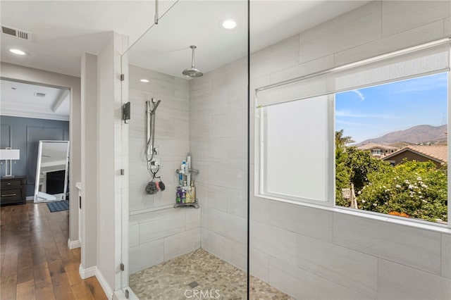 full bathroom with wood finished floors, visible vents, a wealth of natural light, and tiled shower