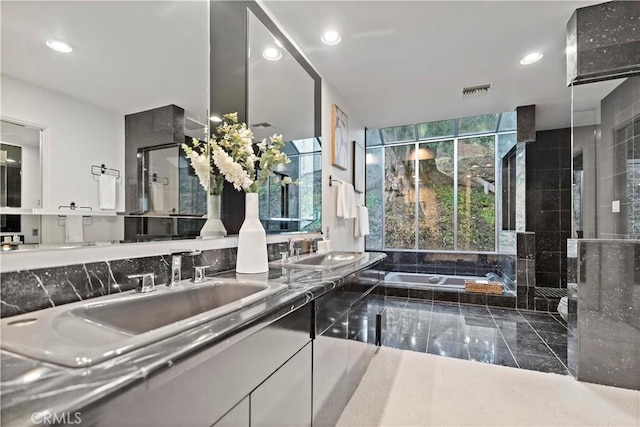 bathroom with double vanity, recessed lighting, a stall shower, a sink, and a bath