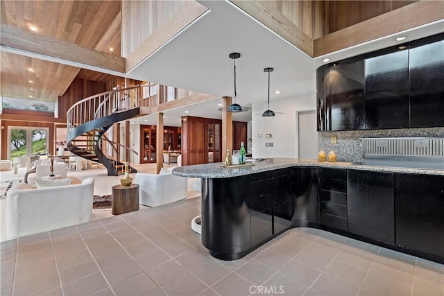 kitchen featuring backsplash, open floor plan, light stone counters, wooden ceiling, and a towering ceiling