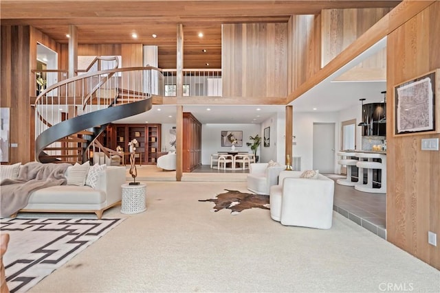 living area with carpet, stairway, wood ceiling, and a high ceiling