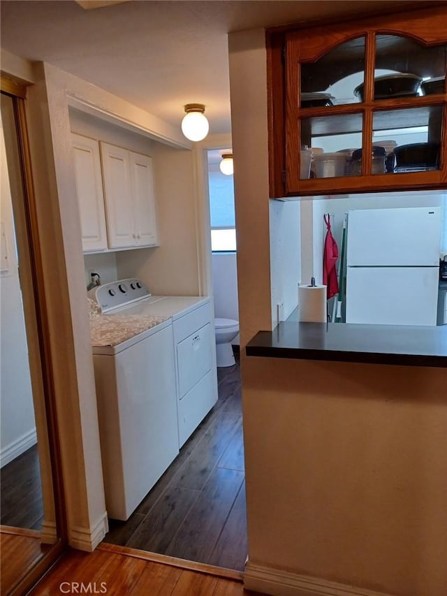 laundry room with dark wood-style floors, separate washer and dryer, and baseboards