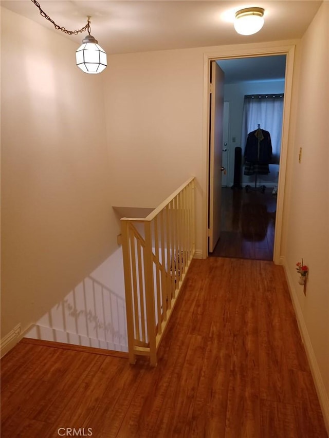 corridor featuring wood finished floors, an upstairs landing, and baseboards