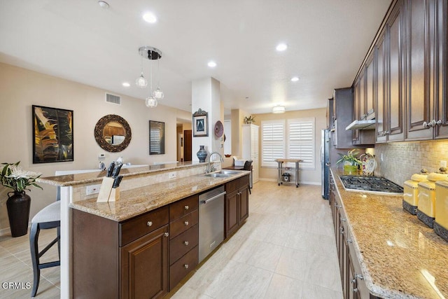 kitchen with visible vents, a breakfast bar, a sink, under cabinet range hood, and appliances with stainless steel finishes