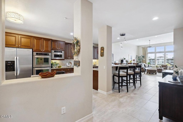 kitchen with light tile patterned floors, recessed lighting, appliances with stainless steel finishes, open floor plan, and backsplash