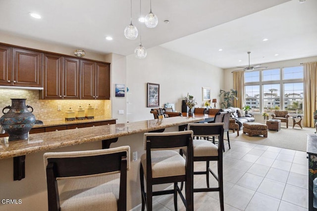 kitchen featuring light stone counters, light tile patterned floors, recessed lighting, hanging light fixtures, and backsplash