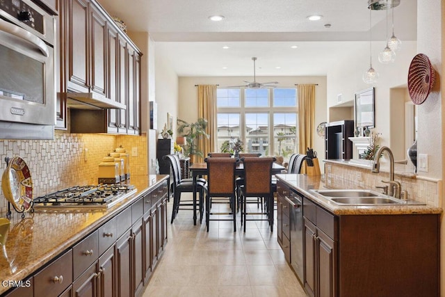 kitchen featuring tasteful backsplash, ceiling fan, decorative light fixtures, stainless steel appliances, and a sink