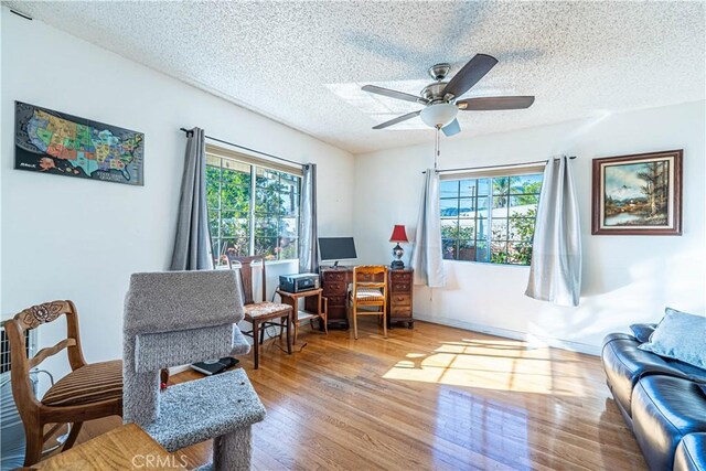 home office with plenty of natural light, a textured ceiling, a ceiling fan, and wood finished floors