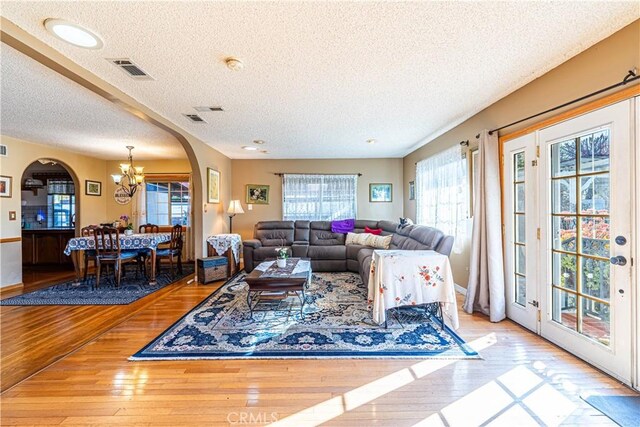 living room with visible vents, arched walkways, plenty of natural light, and hardwood / wood-style floors