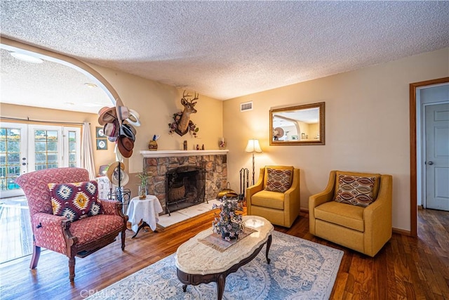 living room featuring visible vents, wood finished floors, french doors, arched walkways, and a fireplace