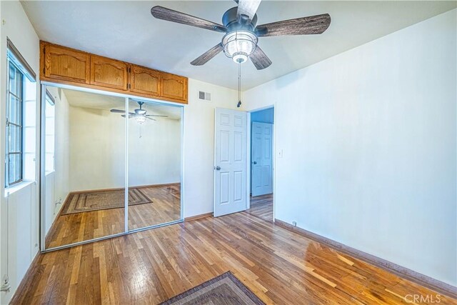 unfurnished bedroom with visible vents, hardwood / wood-style flooring, a closet, baseboards, and ceiling fan