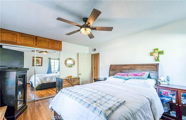 bedroom featuring visible vents, wood finished floors, a closet, a textured ceiling, and a ceiling fan