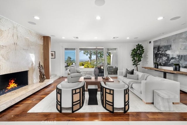 living room featuring a high end fireplace, visible vents, recessed lighting, and wood finished floors