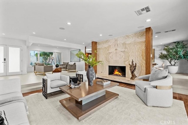 living area featuring recessed lighting, wood finished floors, visible vents, and a high end fireplace