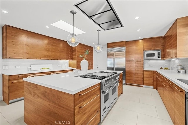 kitchen with tasteful backsplash, a kitchen island, built in appliances, light tile patterned floors, and brown cabinets