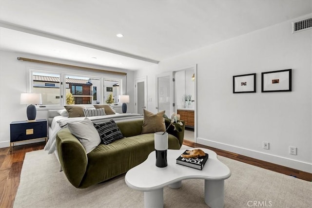 living area featuring visible vents, wood finished floors, and baseboards