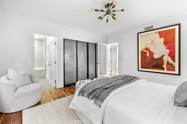 bedroom with visible vents, a closet, wood finished floors, and ensuite bathroom