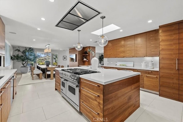 kitchen with brown cabinetry, range with two ovens, light tile patterned flooring, light countertops, and tasteful backsplash