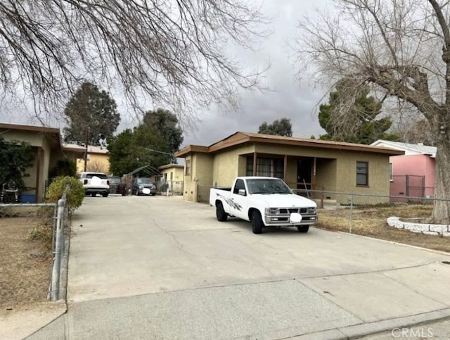 view of front of house with stucco siding, concrete driveway, and fence