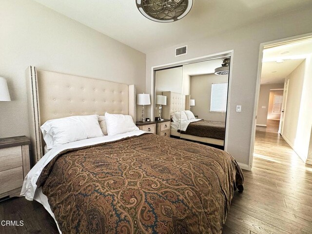 bedroom with visible vents, baseboards, a closet, and wood finished floors