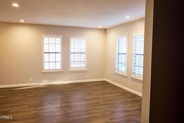 spare room featuring dark wood-style floors, recessed lighting, and baseboards