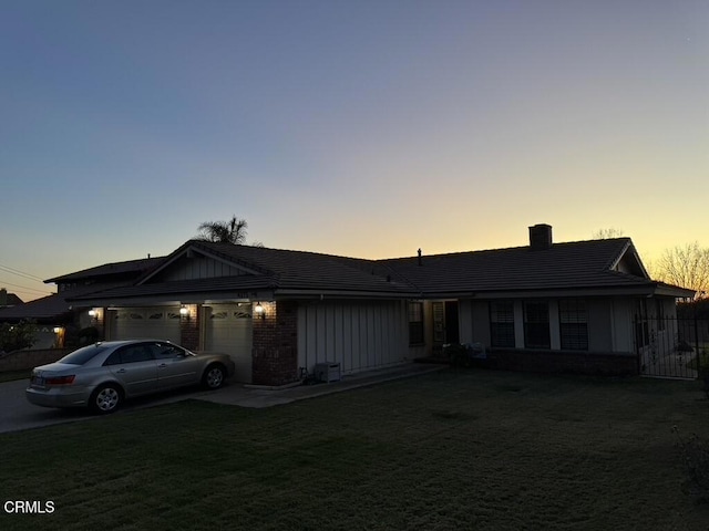 ranch-style house with a yard, board and batten siding, a chimney, and a garage