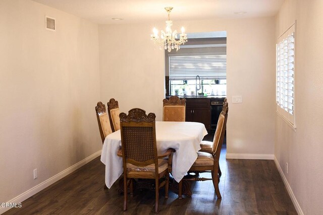 dining space with dark wood-type flooring, visible vents, baseboards, and a chandelier