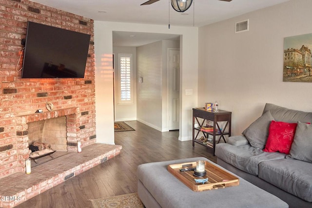 living area with baseboards, visible vents, a fireplace, ceiling fan, and hardwood / wood-style flooring