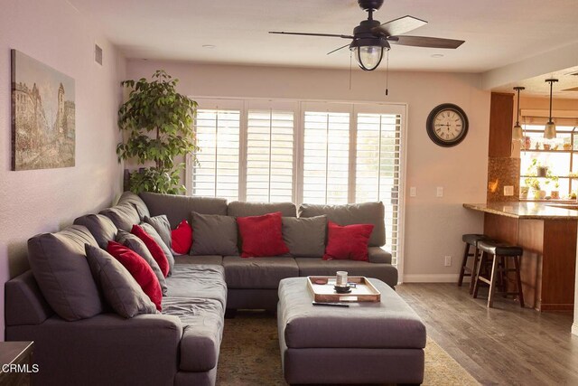 living room with ceiling fan, visible vents, baseboards, and wood finished floors