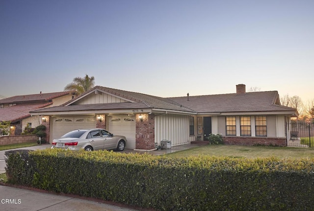 single story home with brick siding, a front lawn, a chimney, a garage, and driveway